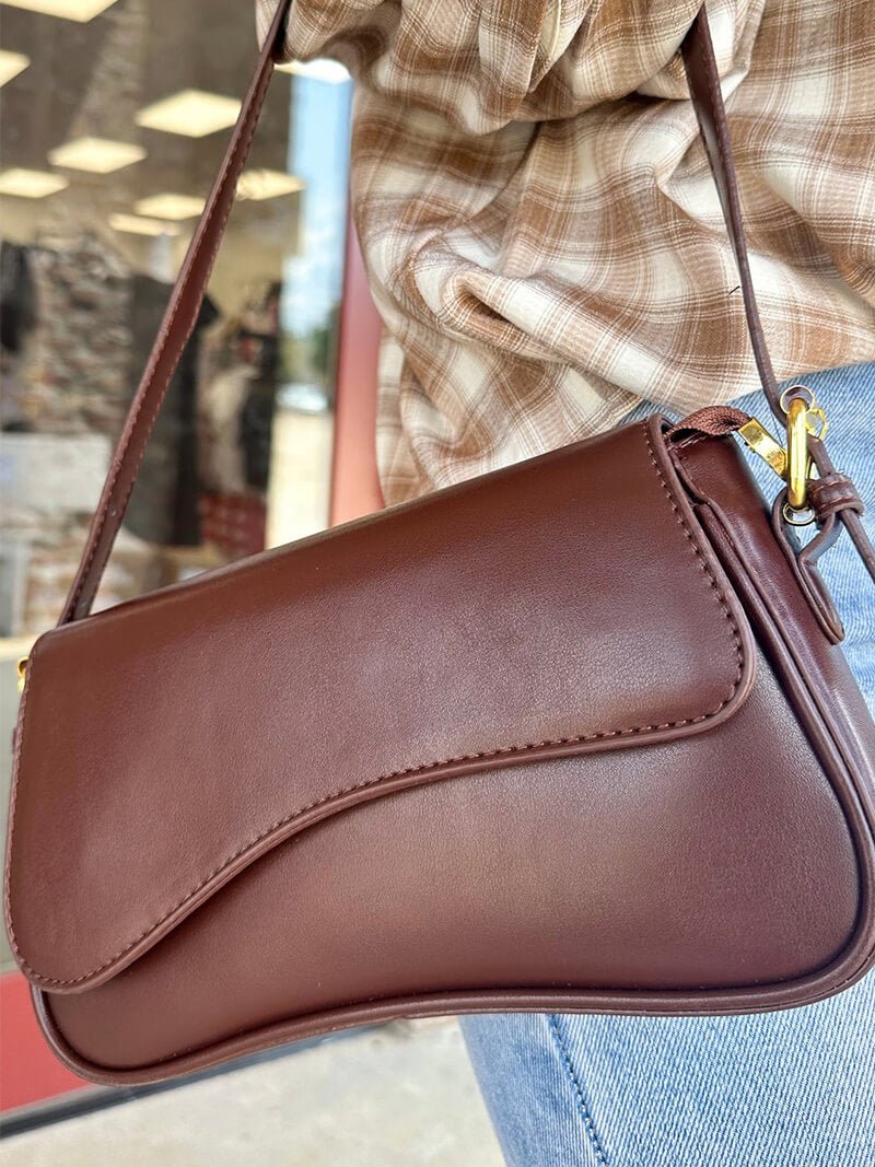 Compact shoulder bag with curved front detail and snap closure