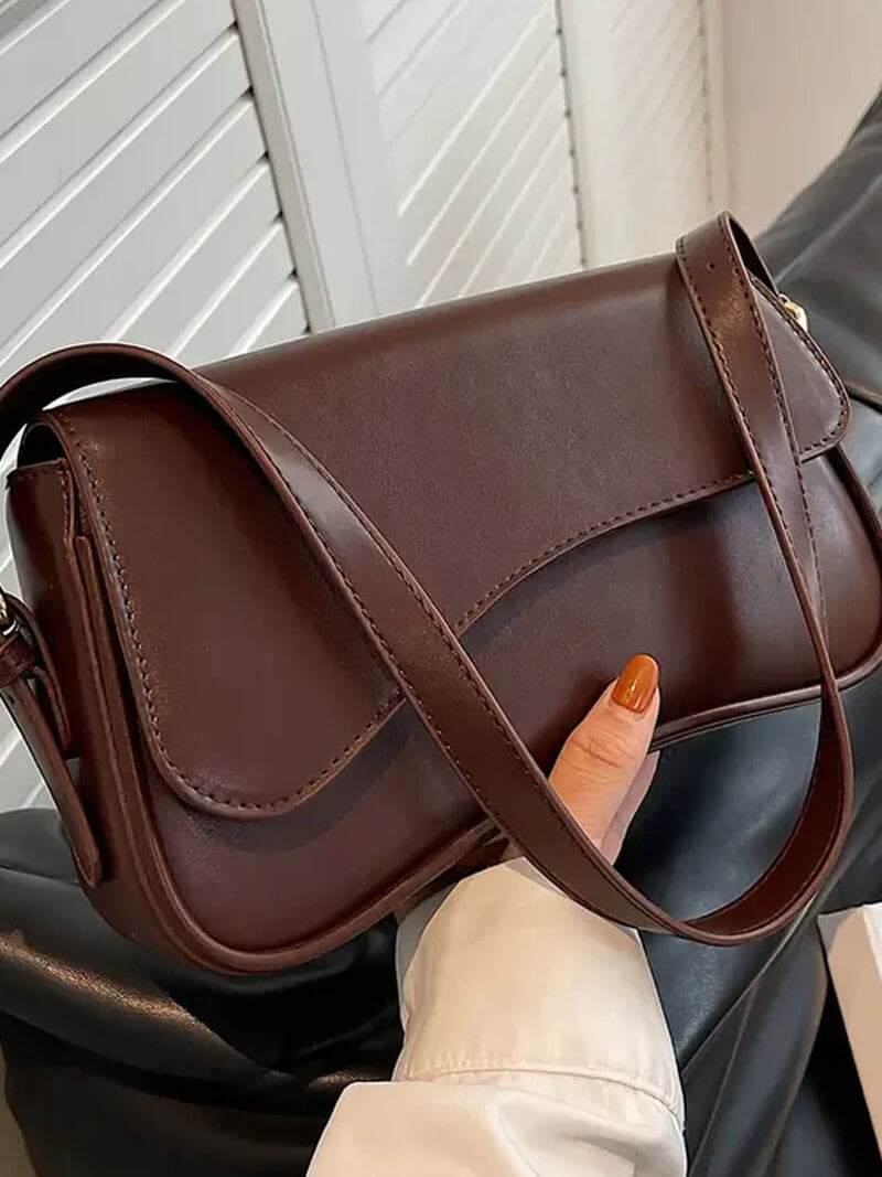 Compact shoulder bag with curved front detail and snap closure