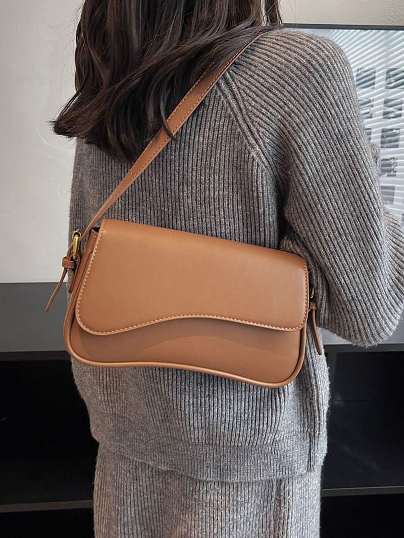 Compact shoulder bag with curved front detail and snap closure
